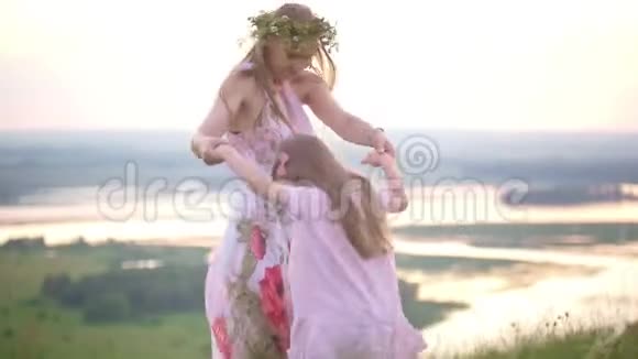 夏天日落时分年轻的母亲和女儿在山上拥抱着视频的预览图