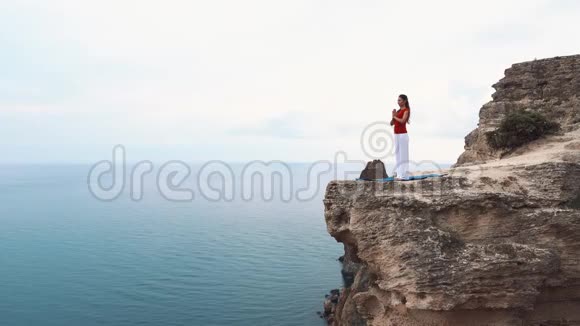 女人站在海边的悬崖上沉思在悬崖上做瑜伽视频的预览图