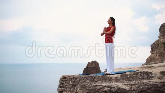 女人站在海边的悬崖上沉思在悬崖上做瑜伽视频的预览图