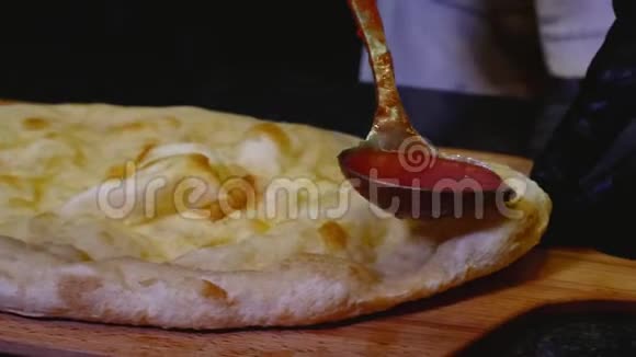 厨师浇番茄酱披萨框架在意大利比萨饼上涂上一瓢番茄酱筹备工作视频的预览图