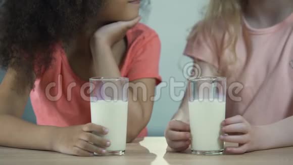 两个多种族的女孩拿着一杯牛奶互相吐舌头视频的预览图