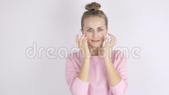 护肤理念年轻女性在脸上涂面霜视频的预览图
