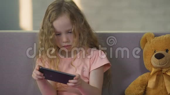 可爱的女孩子在智能手机上享受游戏小玩意成瘾童年视频的预览图
