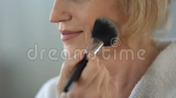 成熟的女人用化妆刷涂面粉准备约会美容视频的预览图