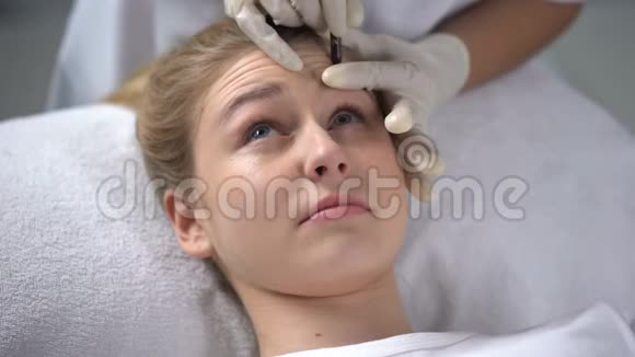 有经验的美容师在女孩额头上刻划皱纹视频的预览图