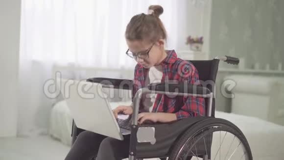 轮椅上的残疾少女使用笔记本电脑的肖像视频的预览图