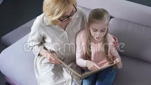 快乐的金发孙女和她关心的祖母一起读书视频的预览图