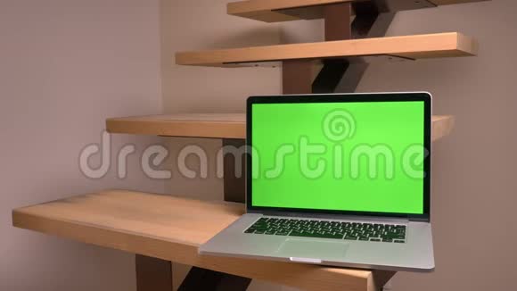 办公室里的楼梯上躺着绿色彩色屏幕的笔记本电脑特写镜头视频的预览图
