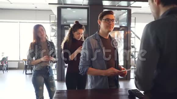 年轻人排队买外卖咖啡早上在咖啡馆用手机付钱成功视频的预览图