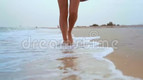 沙滩洗涤海波上行走的鞣质妇女腿特写视频的预览图