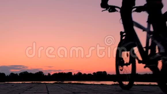 骑自行车的剪影少年骑自行车沿着河堤前行体育生活方式视频的预览图