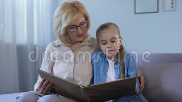 在家里和祖母一起读童话故事的金发孙子视频的预览图