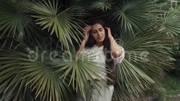 一个年轻的学生在棕榈树林里一位女士在手和手指上视频的预览图