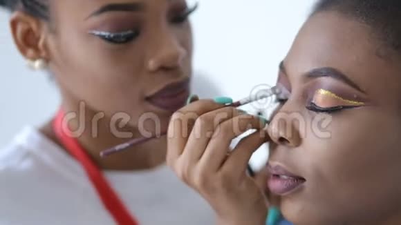 专业化妆师用画笔在迷人优雅的非洲模特眼皮上化妆视频的预览图
