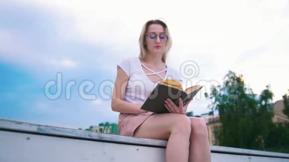 有魅力的年轻女性在户外看书背景蓝天视频的预览图
