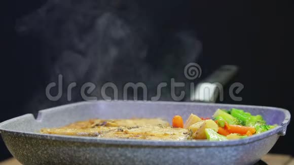 女性用火钳在锅中搅拌鱼和蔬菜视频的预览图