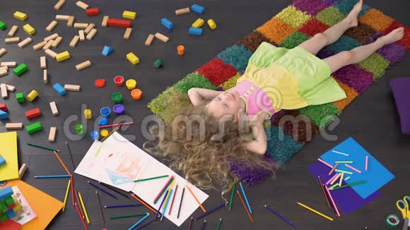 卷曲的金发孩子躺在地毯上梦想和欢笑快乐的童年视频的预览图