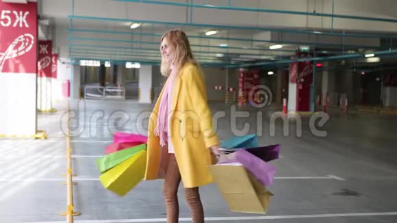 带包的年轻女人购物后很高兴一个金发女人旁边有多种颜色的袋子商店出售视频的预览图