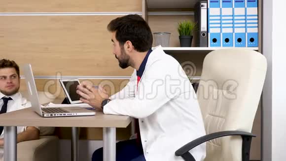 医生在现代办公室和他的同事谈话视频的预览图