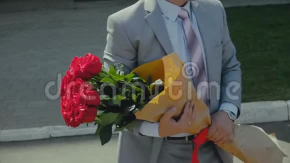 西装革履的男人带着一束玫瑰周年纪念或生日快乐的礼物视频的预览图