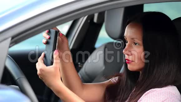 漂亮的年轻女孩在智能手机上自拍在车里微笑视频的预览图