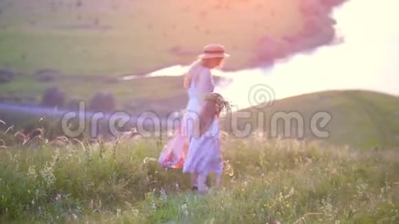 母亲牵着女儿下山在夏日的夕阳下河上有美丽的景色视频的预览图
