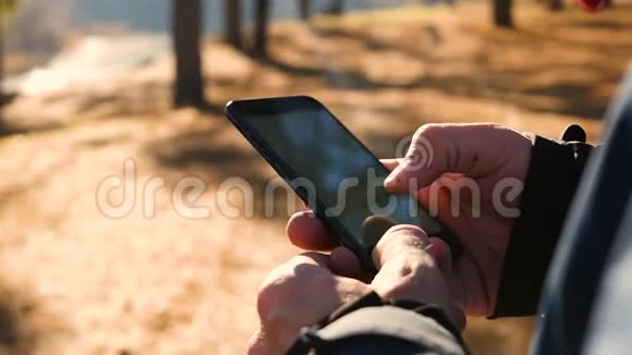 在寒冷的季节一个穿着温暖衣服的男人用他的智能手机触摸触摸屏特写镜头视频的预览图