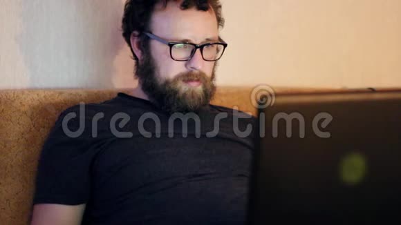 一个留着胡子和眼镜的人在家里的电脑里工作远程工作的概念视频的预览图