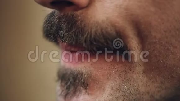 男性用电动剃须刀仔细梳理他的胡须极端特写视频的预览图