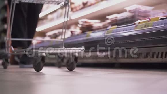 一个男人把商品放进超市的推车里视频的预览图
