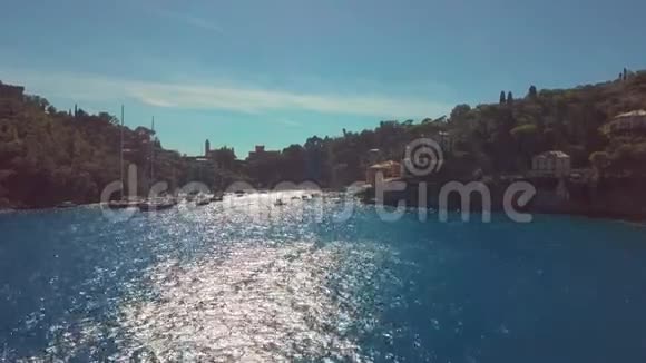 意大利的波尔图菲诺船只在夏季阳光明媚的日子穿过靠近沿海城镇的海峡空中景观视频的预览图