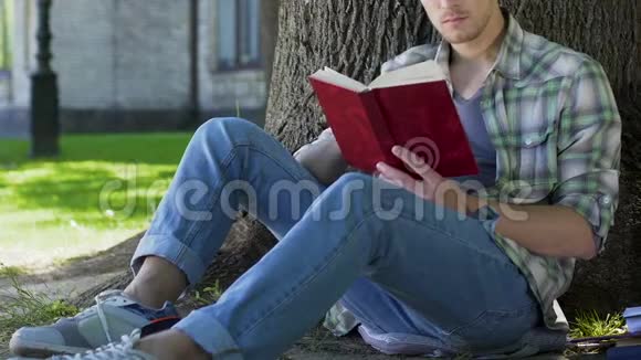 大学生男学生坐在树下读书促进自我发展视频的预览图