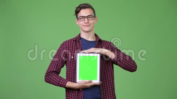 年轻英俊的青少年书呆子男孩展示数码平板电脑视频的预览图