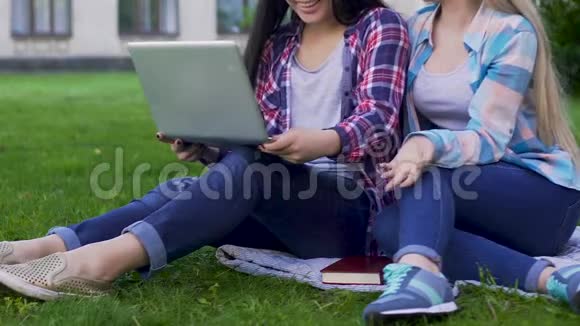 两名女生在草坪上拿着笔记本电脑进行讨论交友视频的预览图