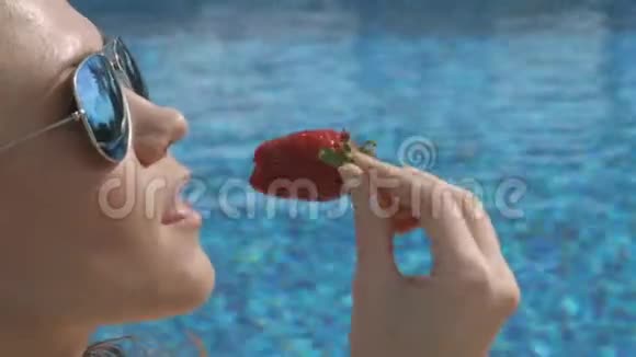 迷人的女人诱人地在泳池边吃甜草莓夏天调情视频的预览图