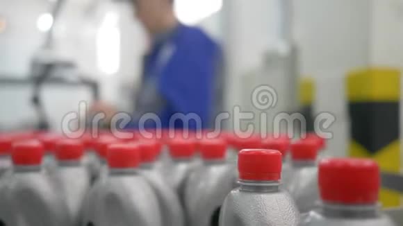 机油厂在工人附近的室内带红色盖子的灰色塑料瓶在传送带上绕一圈移动视频的预览图