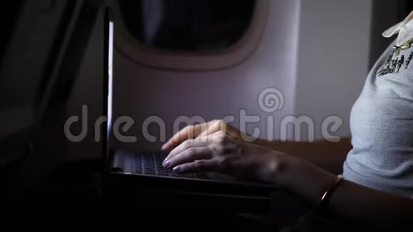 手在笔记本电脑特写上打字女人晚上在飞机上工作视频的预览图