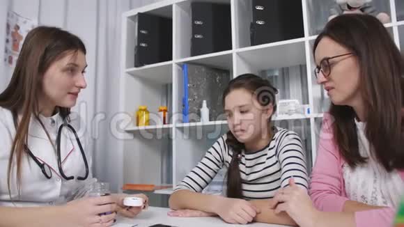 母亲和女儿是一个十几岁的孩子正在接受医生的接待医生给青少年一种维生素以增强免疫力视频的预览图