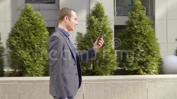 一个年轻的商人走在街上高兴地在视频电话上交流视频的预览图