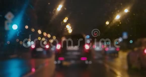 缓慢行驶的汽车在雨中开着后灯透过潮湿的窗户看视频的预览图