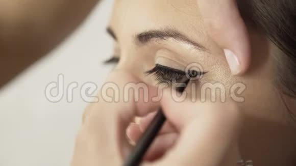 化妆师用黑色眼线画一个金发女孩的眼睛视频的预览图