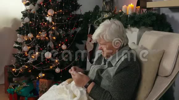 一位坐在椅子上的老妇人编织一条毯子视频的预览图