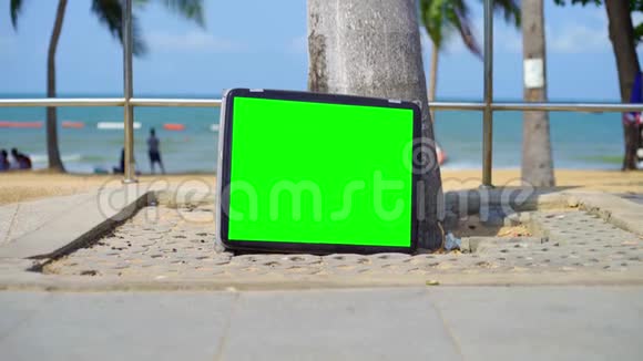 电视站在海滩上带有绿色屏幕的电视你可以用你想要的镜头或图片代替绿色屏幕视频的预览图