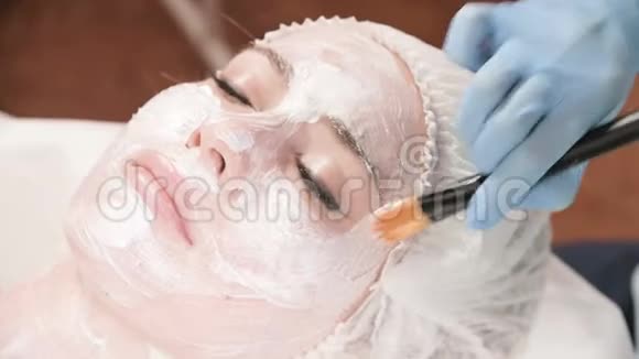 这个美容师的女孩做清洁和滋润皮肤的手术敷一个带特殊面膜视频的预览图