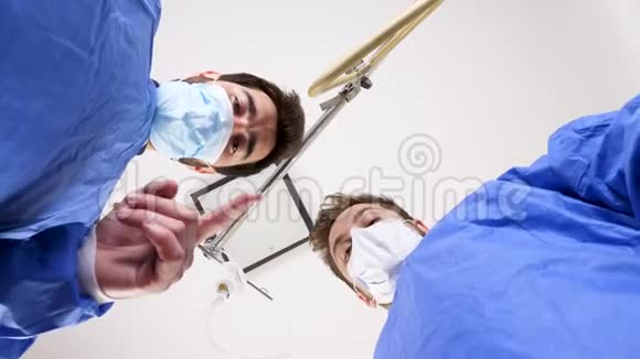 两名手术成功后的外科医生正在病人头上讲话视频的预览图