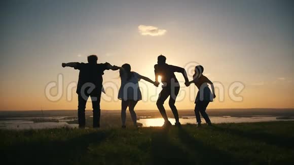 一群快乐的青少年举起双手在夕阳下跳跃视频的预览图