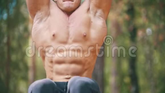 强壮的男人在森林中的横杆上挥舞腹肌视频的预览图
