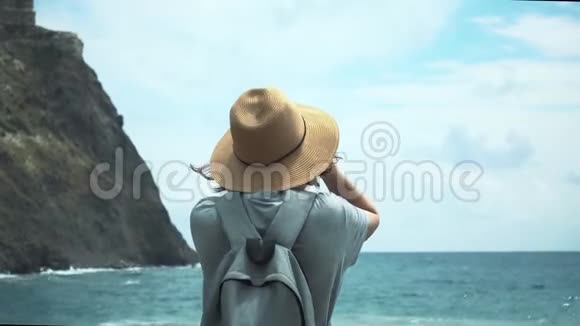 戴着帽子的年轻旅游女孩欣赏美丽的海景视频的预览图