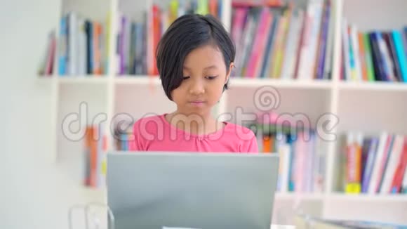 小学生在图书馆使用笔记本电脑视频的预览图