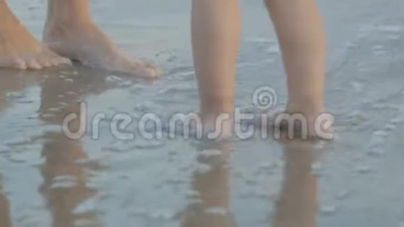 白人年轻女子和两岁的婴儿在日落海滩上玩耍妈妈和女儿的腿靠近大海视频的预览图
